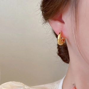 Macro view of minimalist C-shaped thick gold hoop earring with a geometric design