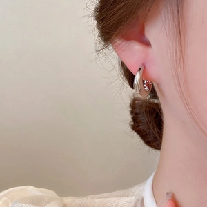Close-up of minimalist chunky silver hoop earring worn by a model in warm light