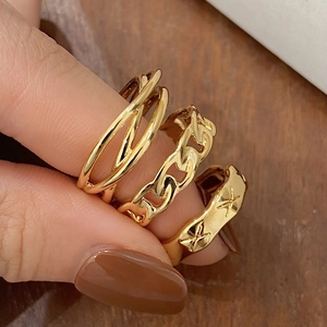 Detail of three gold geometric rings with chain design and engraved star patterns