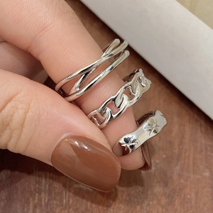Detailed view of silver minimalist three-piece ring set including Cuban chain and star design