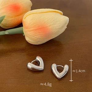 Close-up of heart-shaped silver earrings on wood with 1.4cm height and 4.8g weight tags