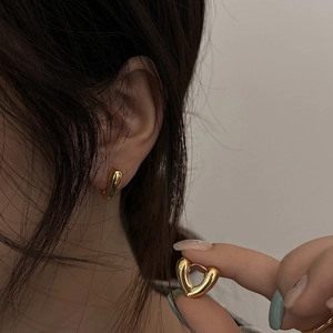 Polished gold heart hoop earrings for women with a minimalist chunky design on ears