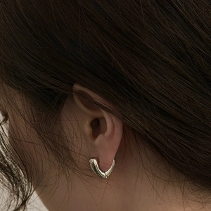 Minimalist silver V-shaped heart earrings with a polished mirror finish on model