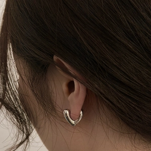 Detailed view of polished silver heart-shaped earring on a model's ear