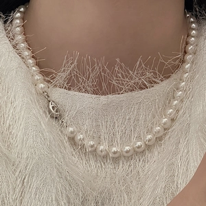Primo piano di un'elegante collana di perle bianche tonde con chiusura in argento al collo