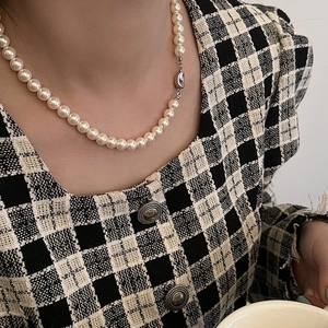 Dettaglio collana di perle stile francese con chiusura a barretta su giacca tweed