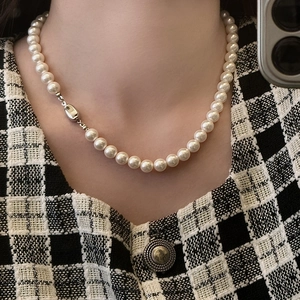 Dettaglio di una collana di perle bianche con chiusura in argento indossata su una modella