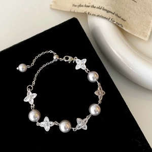 Macro detail of elegant silver bracelet with grey pearls and zircon clover charms