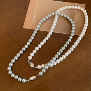 Dettaglio di collane di perle tonde bianche e grigie con eleganti fermagli argentati