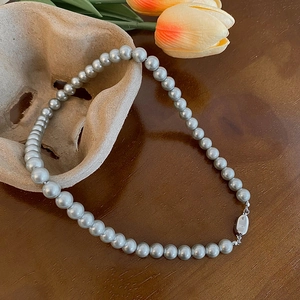 Primo piano della collana di perle con chiusura ovale in argento su legno scuro
