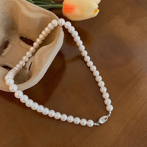 Dettaglio della collana di perle bianche tonde con chiusura argento su legno vintage