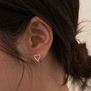 Orecchini a cerchio a cuore cavo in metallo argento indossati da una modella in un primo piano