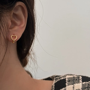 Dettaglio ravvicinato di un orecchino a forma di cuore dorato indossato da una modella