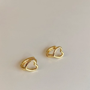Dettaglio macro di orecchini huggie a cuore cavo in oro con finitura minimalista chic