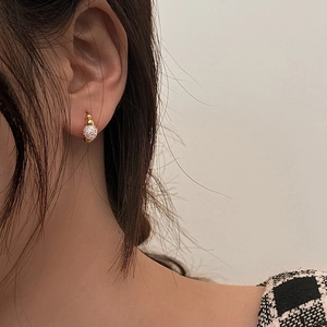 Macro shot of gold-plated hoop earring with a sparkling pavé crystal-encrusted ball drop