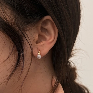 Elegant gold-plated spherical stud earrings with micro-paved crystals on female model