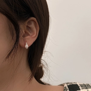 Close-up of silver-plated full crystal ball stud earring worn on model's ear