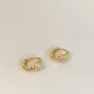 Detailed view of gold hoop earrings with wave texture and crystal-encrusted spheres