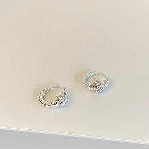 Macro detail of silver pavé crystal ball hoop earrings with textured beaded band