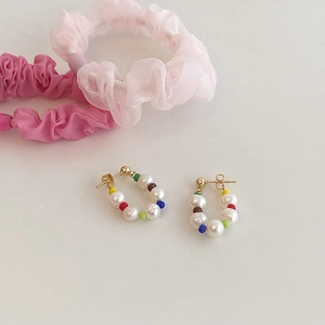Detail of colorful beads and freshwater pearl earrings with gold-toned metal pins
