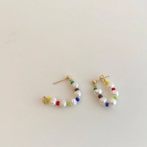 Detail of bohemian hoop earrings with freshwater pearls and colorful beads on white background