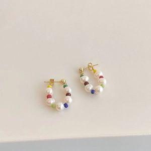 Detailed shot of handmade colorful seed bead and pearl hoop earrings with gold studs