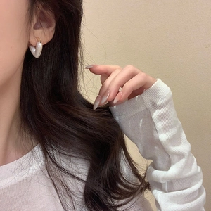 Close-up of vintage heart-shaped pearl earrings in gold plating worn by a model