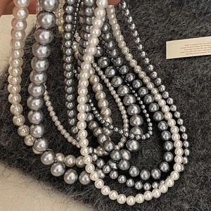 Collane di perle stile francese in bianco e grigio su fondo in maglia grigio scuro