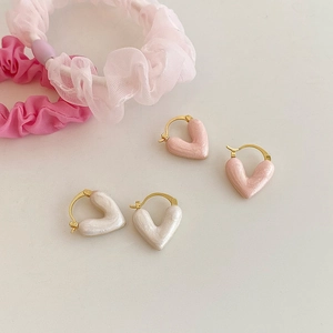 Close-up of pink and white heart earrings with pearlescent finish and gold hoops
