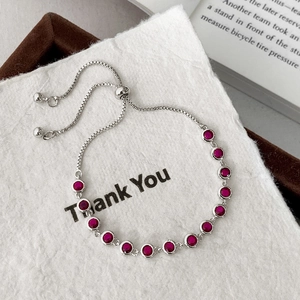 Detailed view of silver adjustable chain bracelet featuring fourteen inlaid red round stones