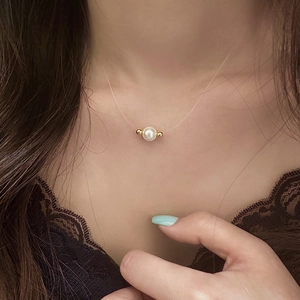 Close-up of a minimalist single pearl pendant floating on an invisible fishing line necklace