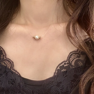 Minimalist pearl necklace with gold beads on transparent wire shown on neck model