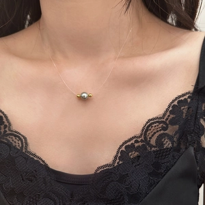 Detail of grey pearl pendant on invisible fishing line necklace worn by model