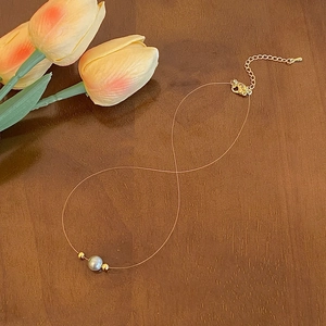 Detail of invisible fishing line necklace with a grey pearl and gold lobster clasp