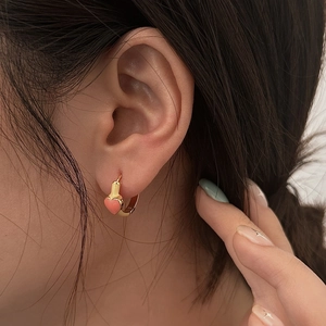 Detailed view of elegant gold hoop earrings with a small pink enamel heart pendant