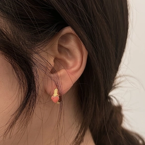 Elegant gold hoop earrings with pink heart charms worn by model for a stylish look