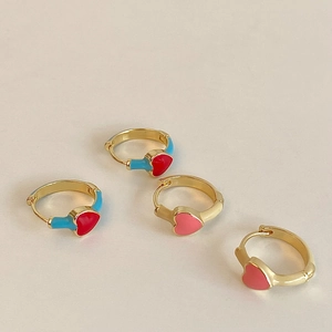 Detail of elegant gold-plated huggie earrings with red enamel hearts and colorful accents