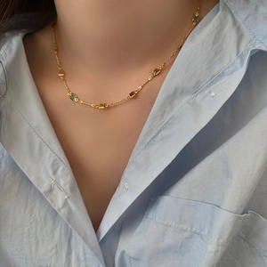 Gros plan du collier doré avec pierres précieuses carrées colorées sur chemise bleue