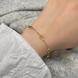 Détail d'un bracelet doré avec trois pierres précieuses carrées et chaîne réglable