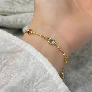 Bracelet élégant en or avec pierres précieuses carrées colorées sur poignet