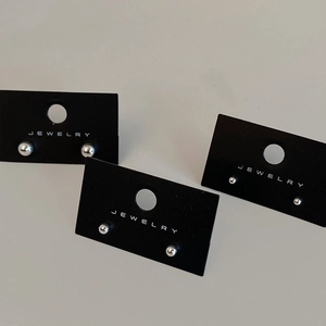 Detailed view of silver minimalist ball stud earrings on black jewelry display cards