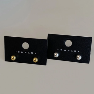 Detail of minimalist gold and silver ball stud earrings set on jewelry card packaging