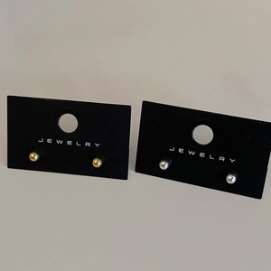 Close-up of minimalist gold and silver ball stud earrings on black display card
