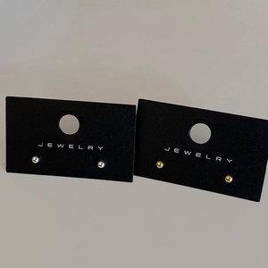 Detail of minimalist gold and silver ball stud earrings on black jewelry display cards