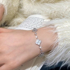 Detail of silver clover bracelet with sparkling zircons worn on wrist over soft background