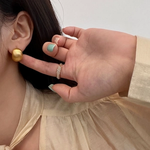 Matte gold egg-shaped stud earrings paired with a pearl and rhinestone open ring