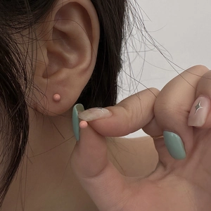 Close-up of minimalist pink round bean stud earrings worn for a delicate aesthetic look