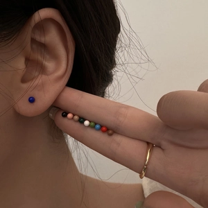Detailed view of colorful round bean stud earrings worn by a model in multiple shades