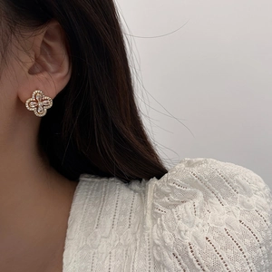 Détail des boucles d'oreilles trèfle dorées avec oxydes de zirconium portées par un mannequin