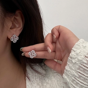 Détail macro de boucles d'oreilles trèfle en zircon brillant portées sur modèle